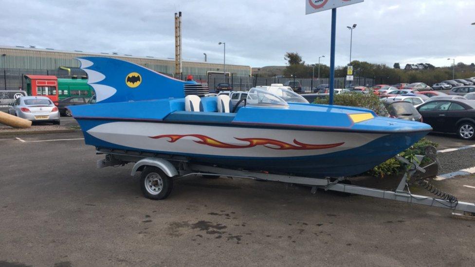 A replica blue bat boat with fire stripes along the bottom and a bat like fin on the back.