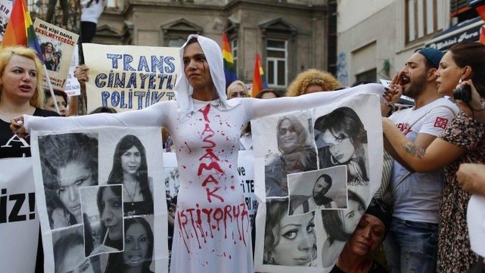 Protesters in Istanbul including an LGBT supporter painted with red tears symbolising blood, her dress reading "I want to live"