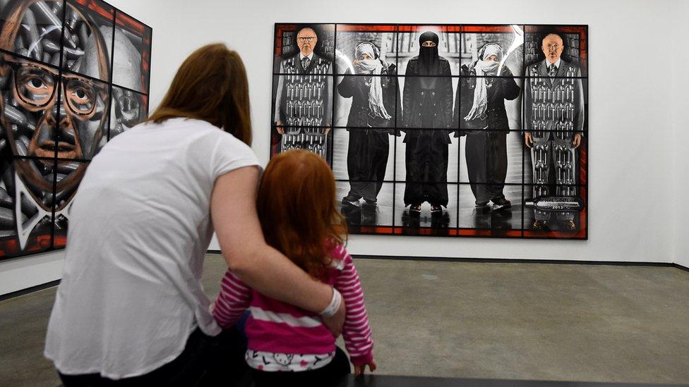 A woman and her child look at an artwork at the opening of the new Gilbert and George exhibition at the Metropolitan Arts Centre (MAC) in Belfast in January 2018