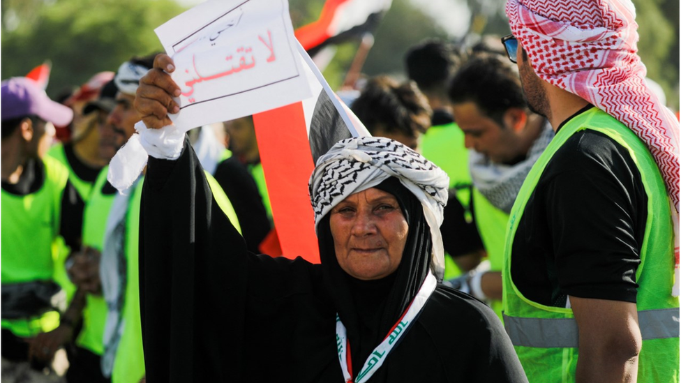 An Iraqi protester holds a sign reading 'Brother don't kill me'