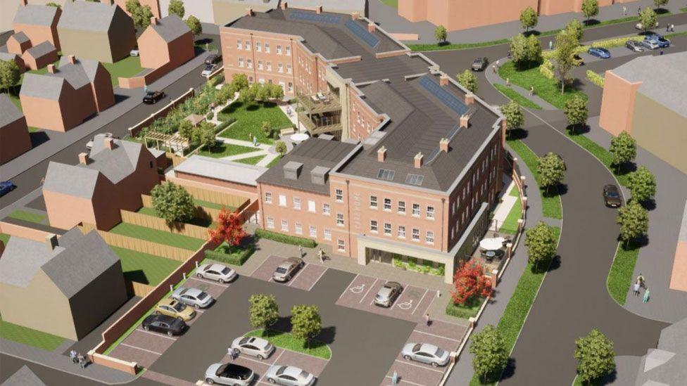 An artist's impression of an aerial view of a three-storey building which is to be a care home. The brick-built traditional-style building is angled up to the top of the image. In the top left can be seen a garden intended for residents. In the bottom of the image is a car park with several parked cars. On either side of the building are roads.