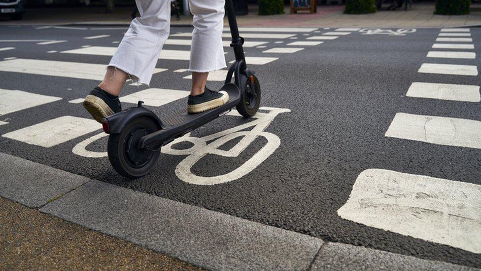 Person riding new e-scooter on road.