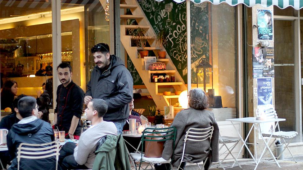 A street scene shows several young people at a restaurant