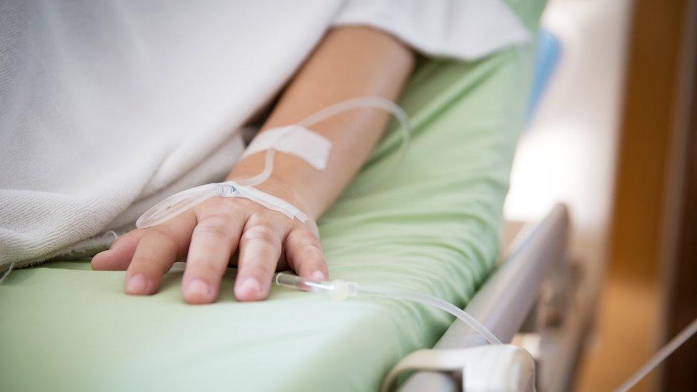 A person on a drip in a hospital bed