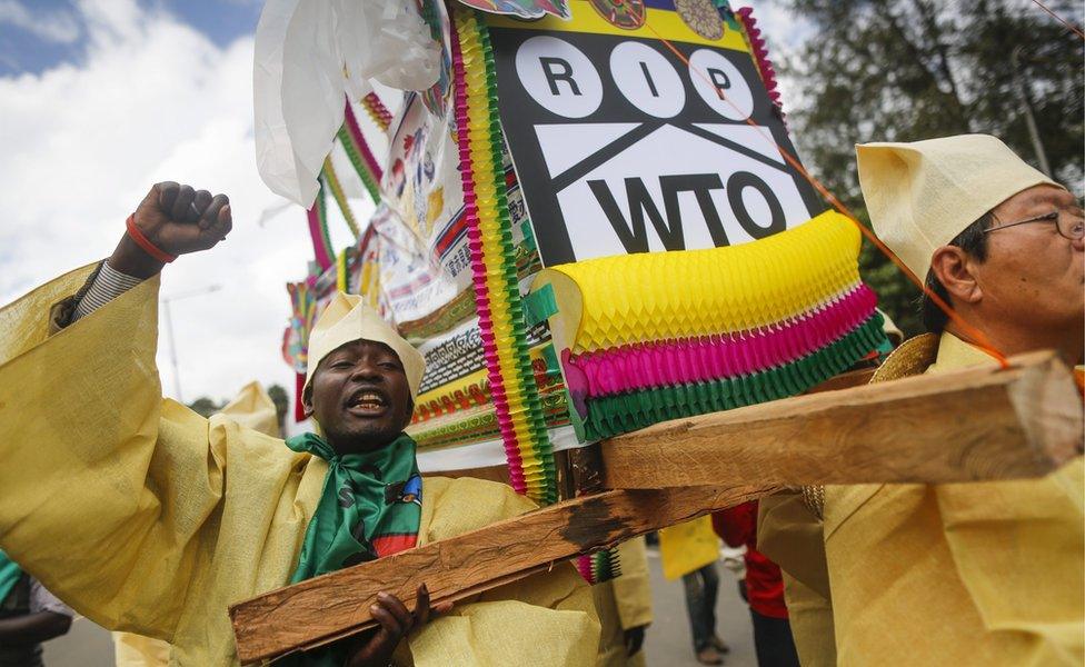 Activists from Kenya and South Korea wearing traditional Korean outfits carry a mock coffin to represent the death of the World Trade Organization (WTO)