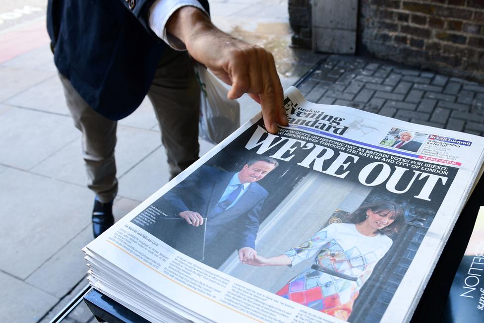 A man takes a copy of the London Evening Standard with the front page reporting the resignation of British Prime Minister David Cameron and the vote to leave the EU in a referendum, showing a pictured of Cameron holding hands with his wife Samantha as they come out from 10 Downing Street,