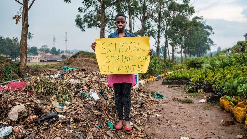 Leah Namugerwa, a 15 year-old climate activist, holds a placard in Kampala on September 4, 2019.