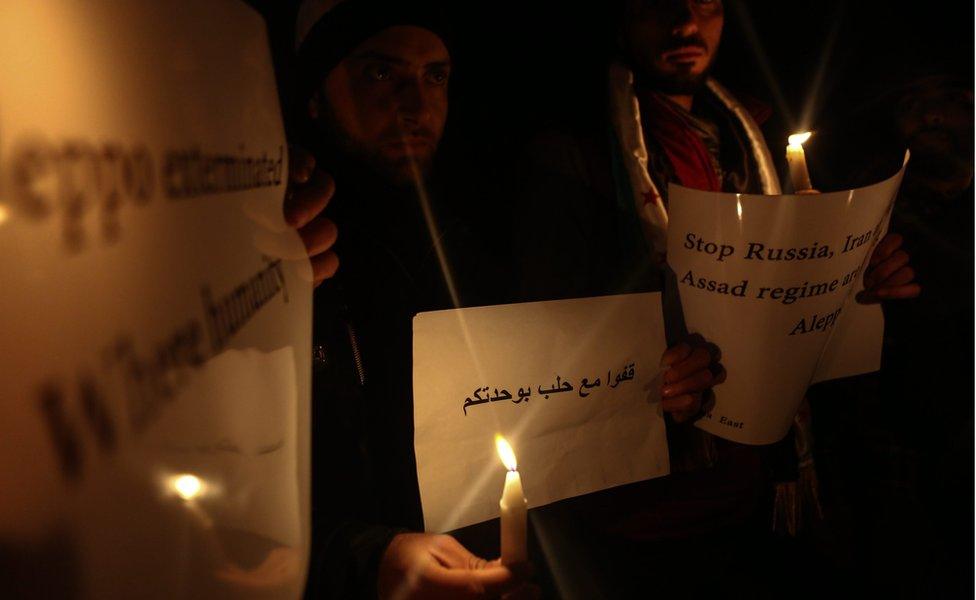 Activists hold banners during a candlelight gathering in solidarity with the people of Aleppo, in light of recent developments reported on the besieged city, in Douma, East Ghouta area, near Damascus,