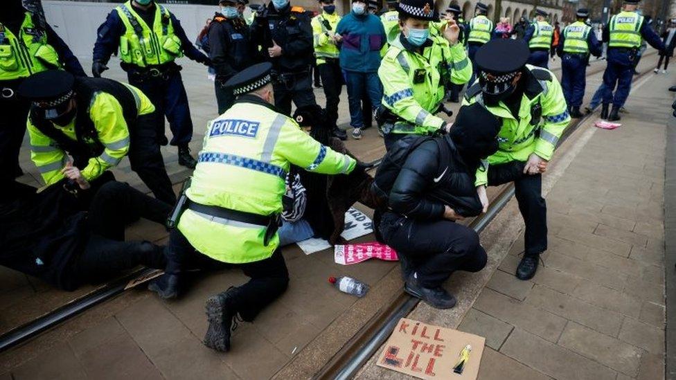 Police officers detain a demonstrator during a protest in Manchester