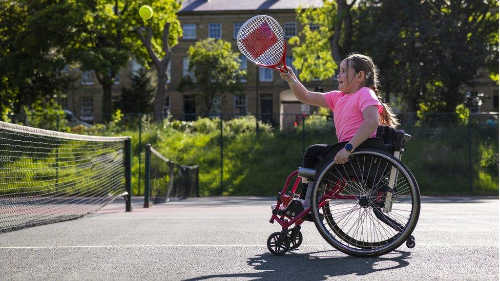 Girl in a wheelchair playing tennis