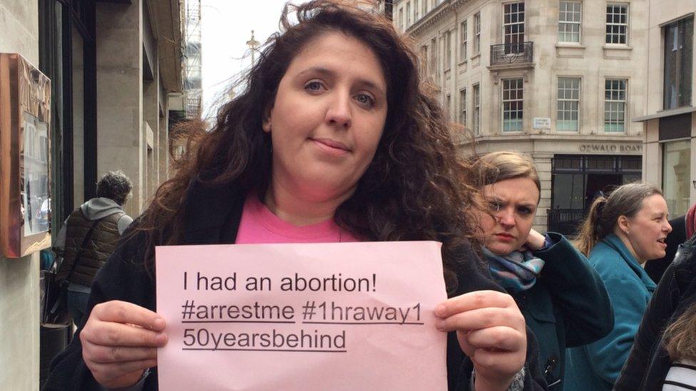 Woman holding a sign reading: "I had an abortion #arrest me #1hraway150yearsbehind"