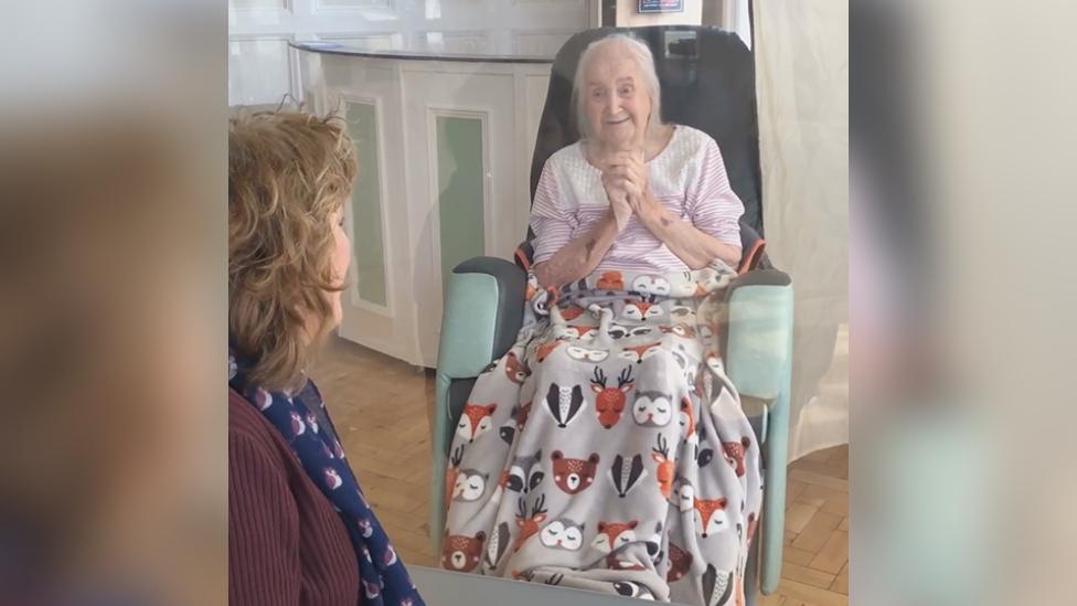 Jacqueline Bright and her mother visiting each other through a Perspex screen