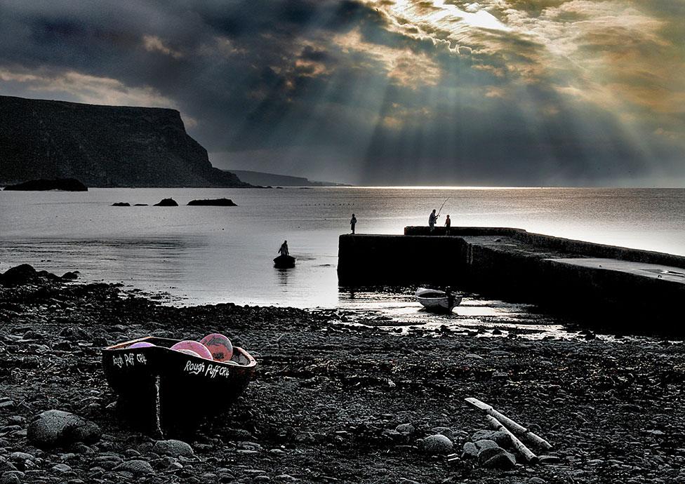 A silhouetted beach and harbour wall