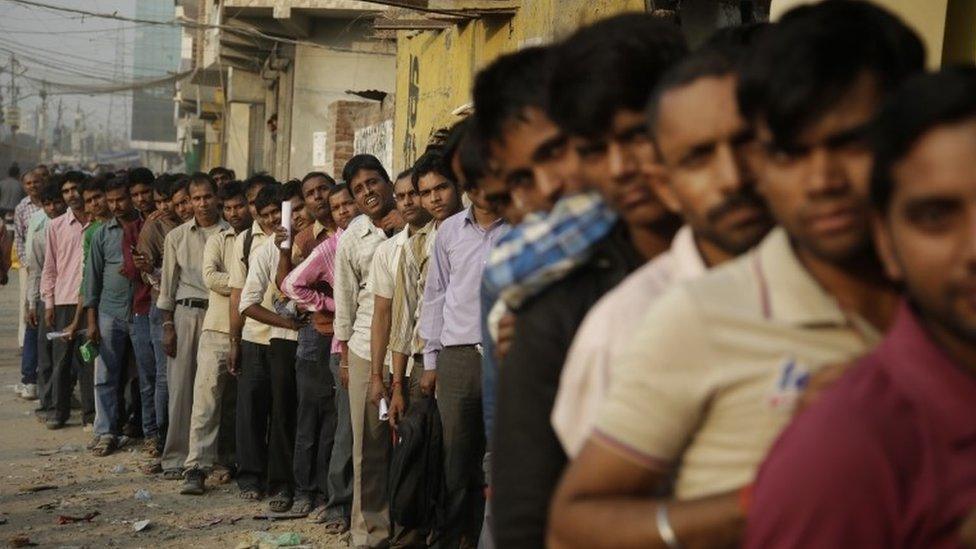 Indians stand in a queue to deposit and exchange discontinued currency notes, outside a bank in New Delhi, India, Sunday, Nov. 13, 2016.