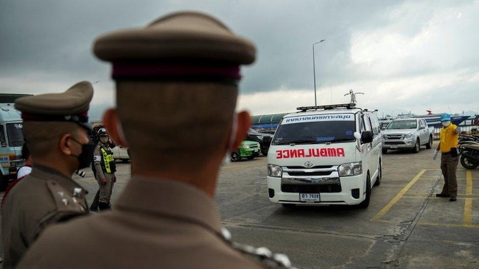 Thai police look on as an ambulance carrying the body of Australian cricket player Shane Warne leaves at a ferry port in Koh Samui, Thailand