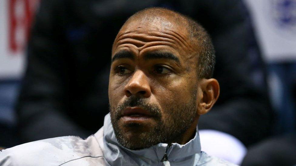 Kieron Dyer pictured sitting in a light grey zip up jacket.