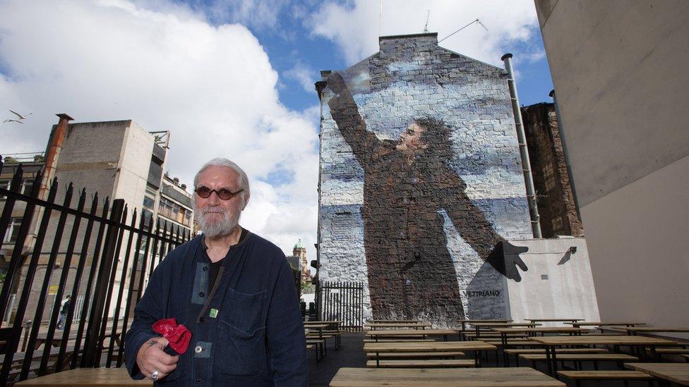 Billy Connolly next to one of his murals