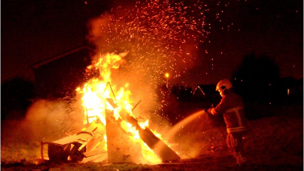 A firefighter putting out a fire outside at night