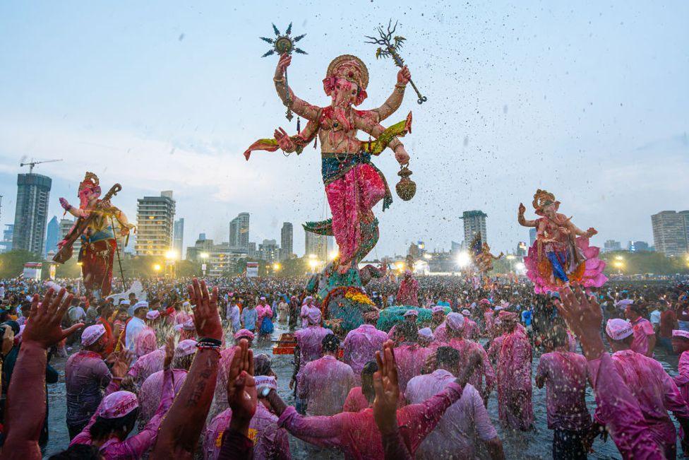 Devotees shower flowers and gulaal, while volunteers immerse an idol of the elephant-headed Hindu god Ganesh at Girgaon Chowpatty beach during the Ganesh Visarjan festival in Mumbai, India, on September 17, 2024. 