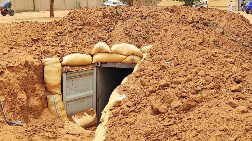 A bomb shelter in the compound of el-Fasher's Saudi Hospital - it shows corrugated iron sheets covered with orange soil and sand bags. 