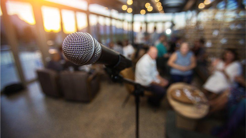 A microphone on a stage with an audience in the background