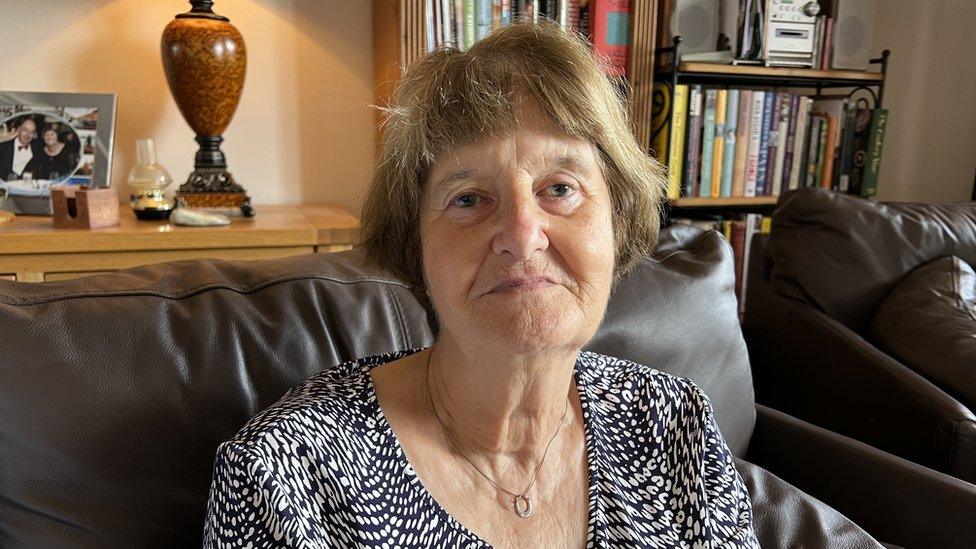 Woman sits on leather sofa and looks at the camera