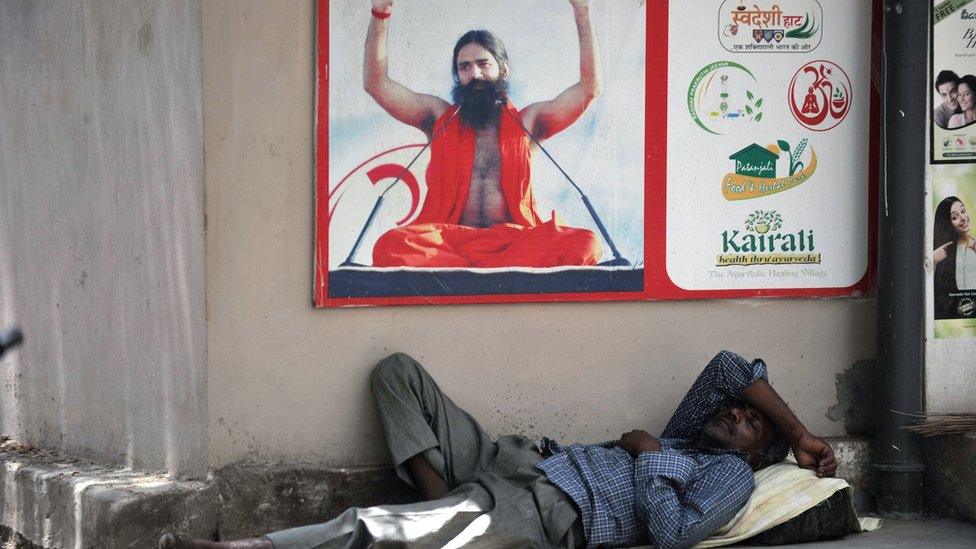 A man sleeps under a poster of yoga guru Baba Ramdev