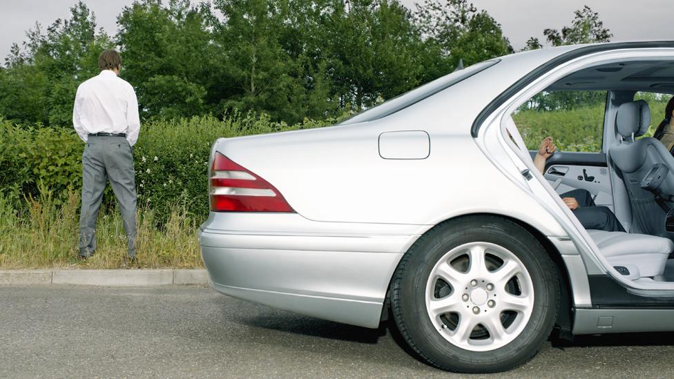 Stock photo of a man urinating at the side of the road