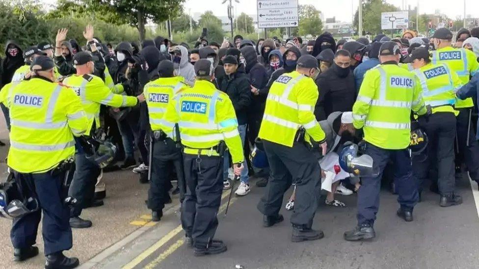 Police officers are trying to keep rival protestors apart on Belgrave Road