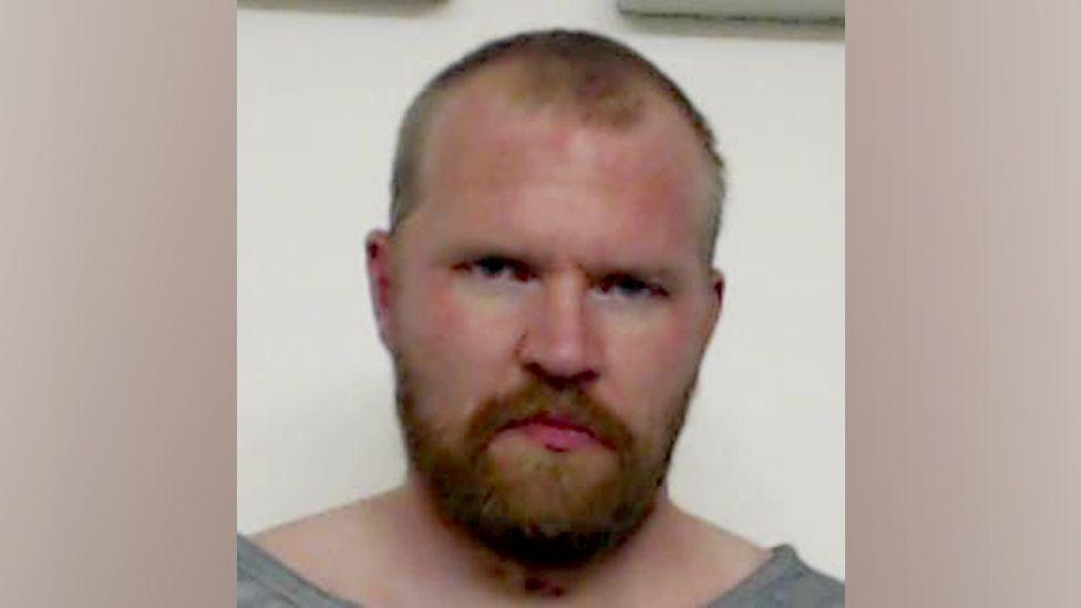 Police mugshot of Aren Pearson looking at camera.