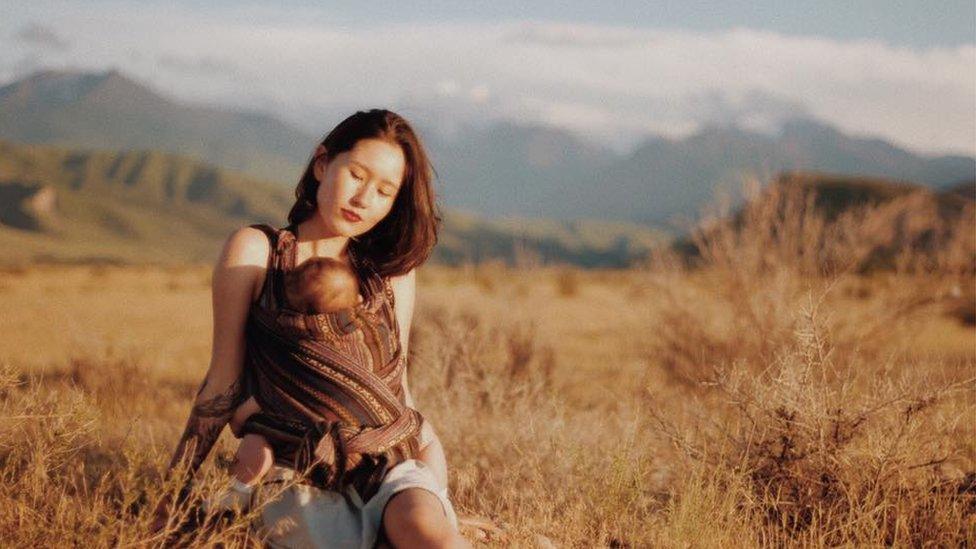 Aliya Shagieva with her baby against the backdrop of Kyrgyz landscape