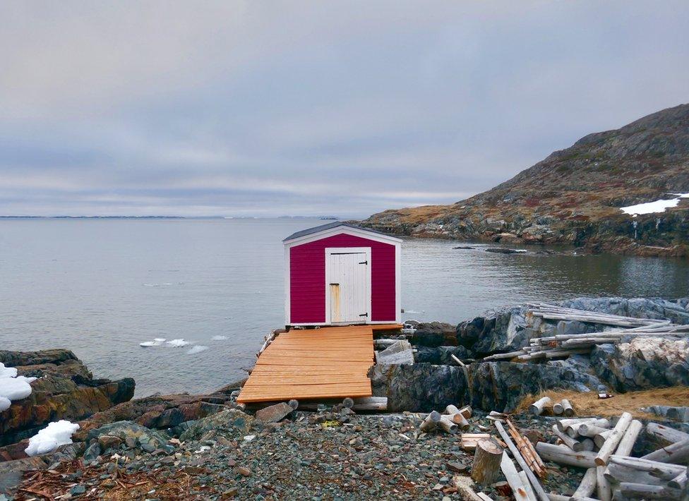 A small red shed sits at the edge of pier overlooking a lake in Vancouver Island