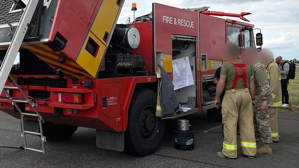 Blurred image op-sec'd (approved for use by MOD) of three Ukrainian military personnel training at RAF Wittering on specialised fire engines