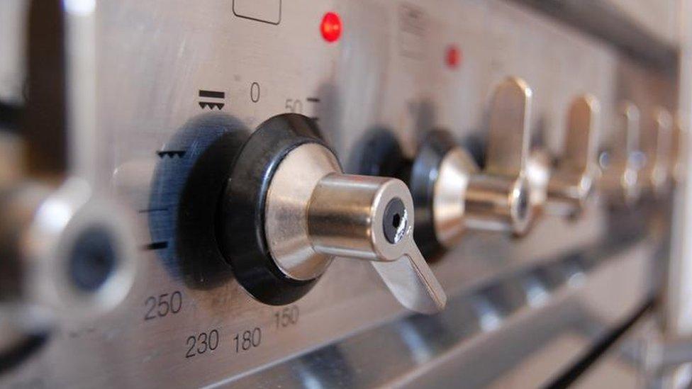 The control knobs along the front of a gas cooker, some are on.