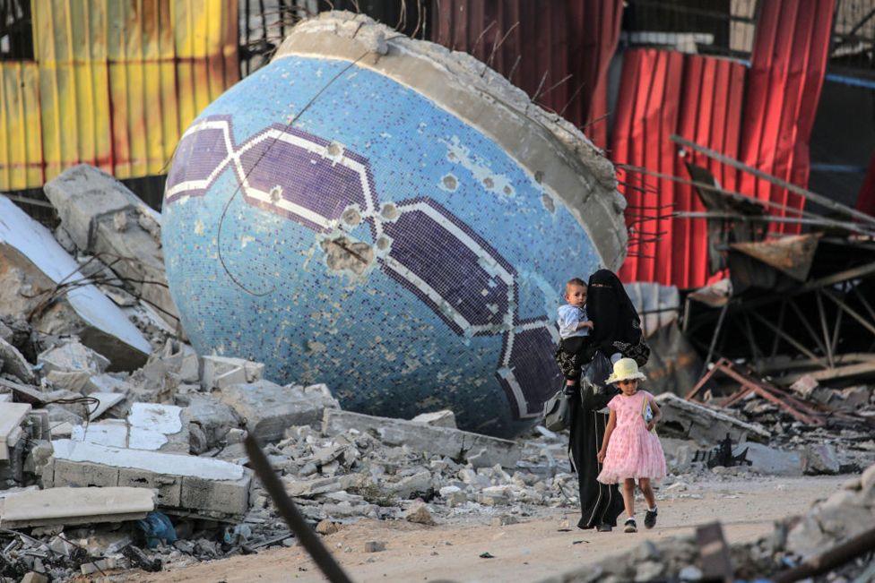 A Palestinian woman and a child walk in front of a mosque destroyed in an Israeli bombardment in Khan Younis in the southern Gaza Strip on May 15 2024