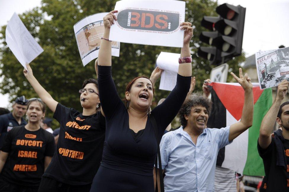 A Pro-Palestinian 'Gaza Beach' protestor holds a placard reading 'BDS (Boycotts, divestment and sanctions) during a gathering on the sidelines of 'Tel Aviv Sur Seine', a beach event celebrating Tel Aviv, in central Paris on August 13, 2015