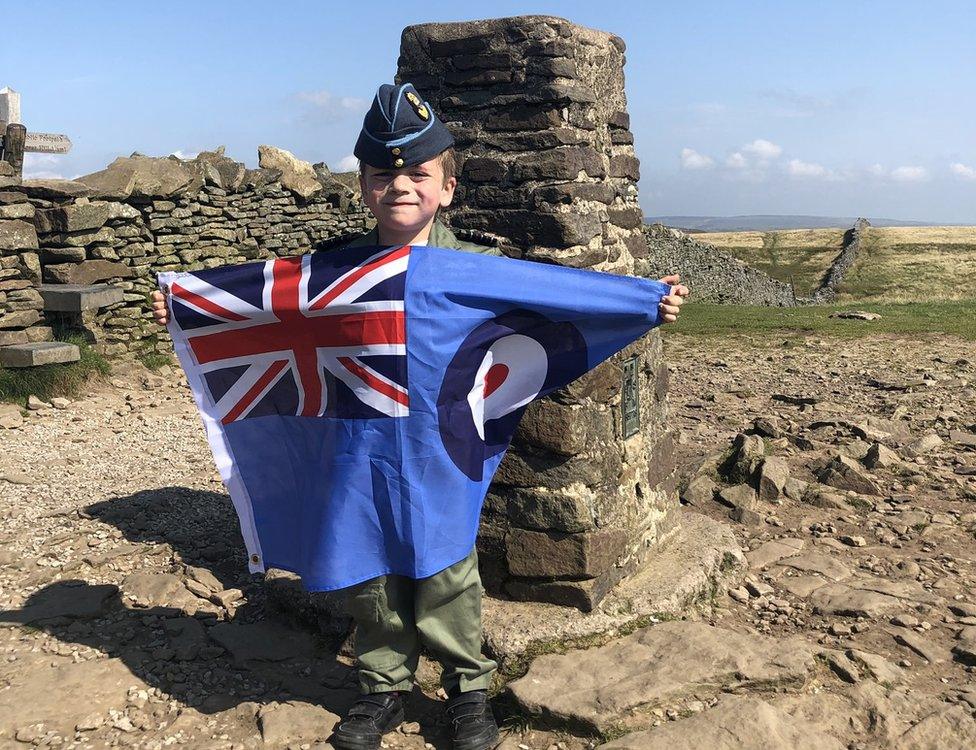 Jacob Newson waving a flag on the top of Pen-y-Ghent