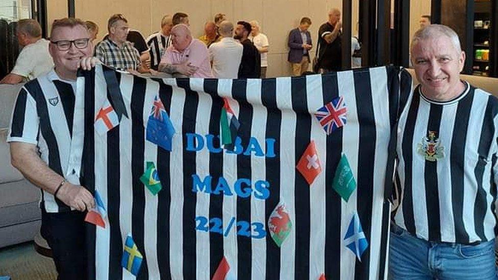 Neil (left) holding a Dubai Mags flag