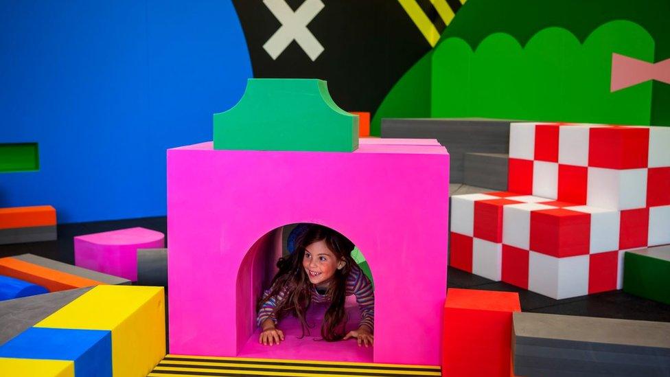 Girl climbing through brightly coloured building blocks at the gallery