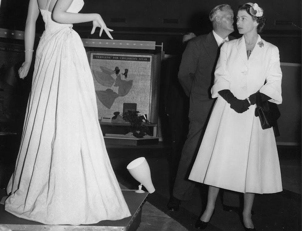 The Queen looks at a dress on a mannequin