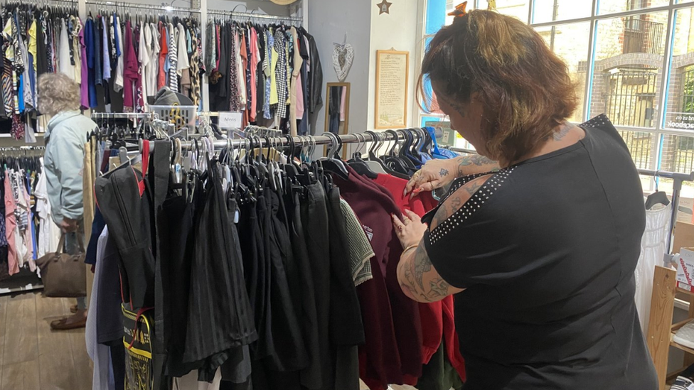 Woman looking at a rack of school uniforms