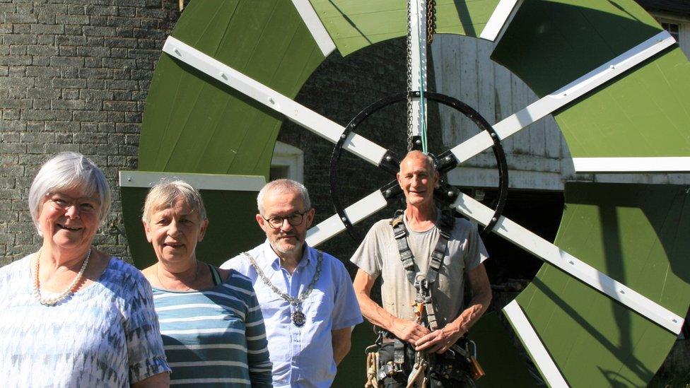 Councillor Melanie Vigo di Gallidoro, (left), Councillor Caroline Page, Councillor Patrick Gillard, and millwright Bill Griffiths, in front of a Woodbridge windmill