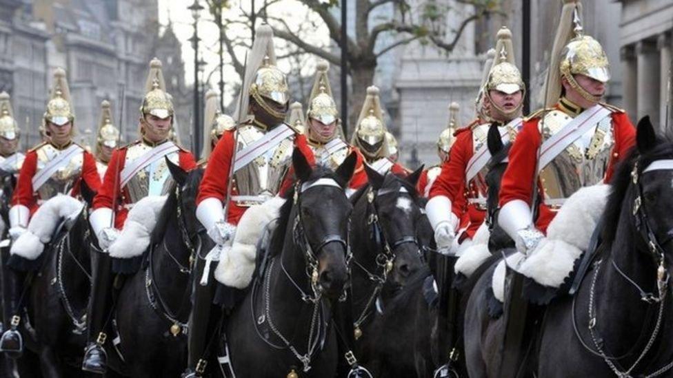 Soldiers on horseback, with gold-coloured helmets, red tunics and black shoes