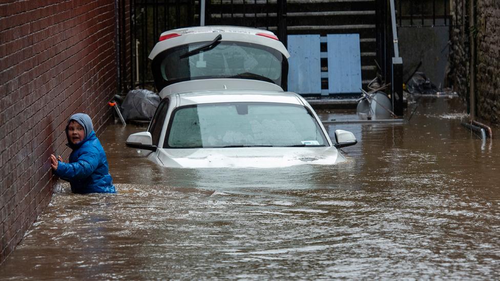 A boy wades towards a flooded alleyway in Pontypridd on Sunday