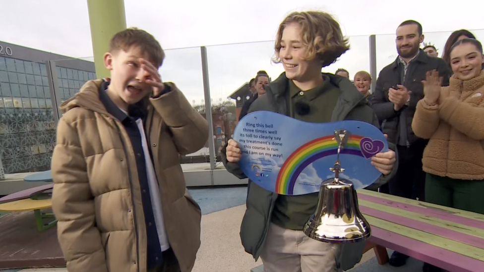 Hughie in tears as he rings the end of treatment bell, held by best friend, Freddie