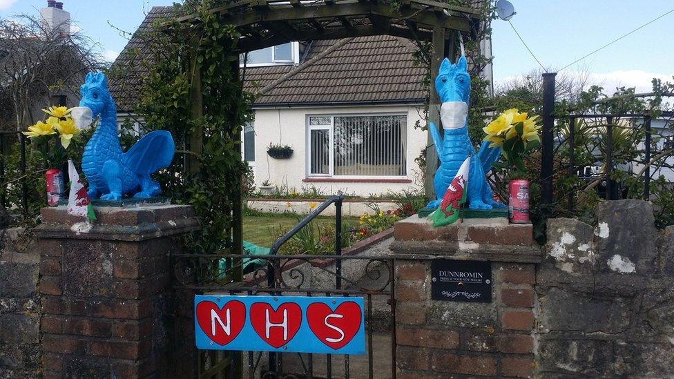 A gate with dragons dressed to look like frontline workers and a sign reading NHS decorated with hearts