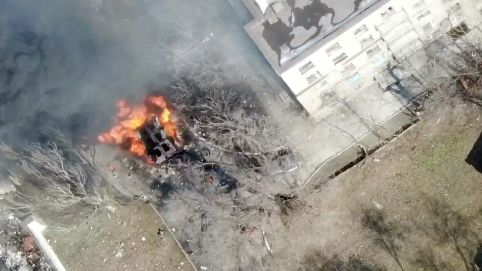 An aeriel view shows a military vehicle on fire next to a building, as Russia's invasion of Ukraine continues, in Maripuol, Ukraine as uploaded on 13 March 2022