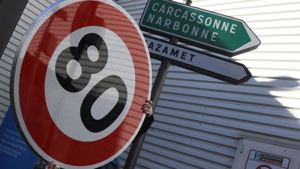 An employee holds a 80km/h traffic sign at the factory of manufacturer Lacroix Signalisation in Saint-Herblain, a suburb of Nantes, on 8 February 2018