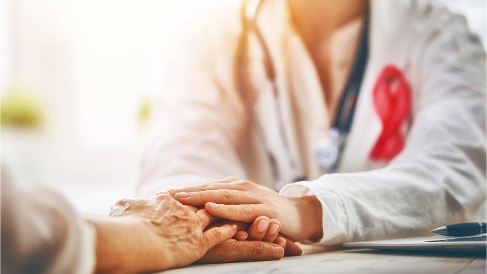 A doctor holds a woman's hands