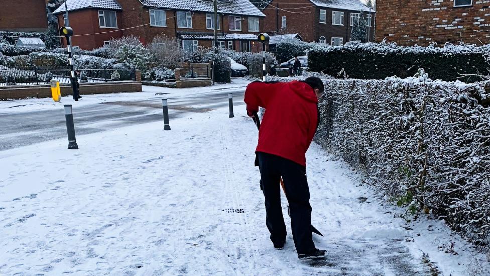 Man clears snow on Whirley Road in Macclesfield